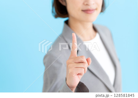 グレーのスーツを着て人差し指を立てるミドル女性ビジネスウーマン 128581845