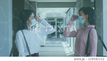 Image of spinning human brain over businesswomen wearing face masks 128582112