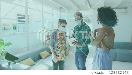 Image of spinning human brain over businesswomen wearing face masks 128582148