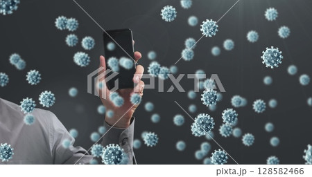 Image of covid 19 cells falling over men holding smartphone on dark background 128582466