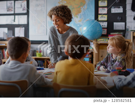 A smiling teacher interacts with elementary school students in a classroom, promoting active learning and engagement. Ideal for education, youth, and mentorship themes 128582581