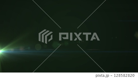 Image of glowing green light moving on dark green background 128582820