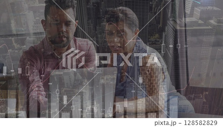 Image of financial graphs, data and cityscape over diverse businesspeople talking in office Image of financial graphs, data and cityscape over diverse businesspeople talking in office 128582829