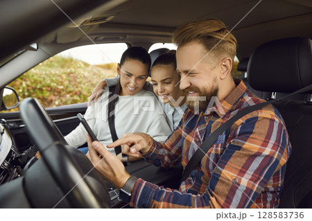 Happy family sitting inside car using digital map application and showing way. Road trip concept. Happy family sitting inside car using digital map application and showing way. Road trip concept. 128583736