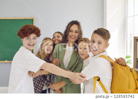 Portrait of a happy schoolchildren with teacher meeting after the holidays in classroom at school. Portrait of a happy schoolchildren with teacher meeting after the holidays in classroom at school. 128583742