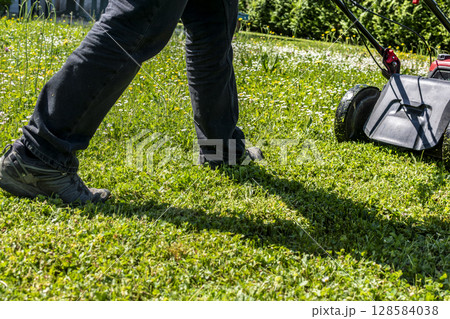 Mowing the lawn with a machine in a garden 128584038