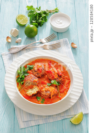 fish cakes in tomato vegetable coconut milk sauce 128584180