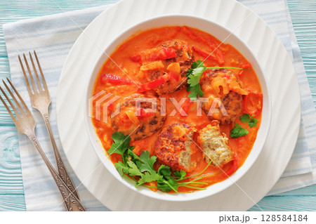 fish cakes in tomato vegetable coconut milk sauce 128584184