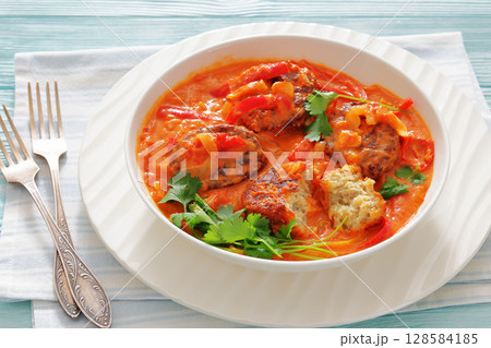 fish cakes in tomato vegetable coconut milk sauce 128584185