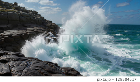 Ocean waves crashing against rocky shore 128584317