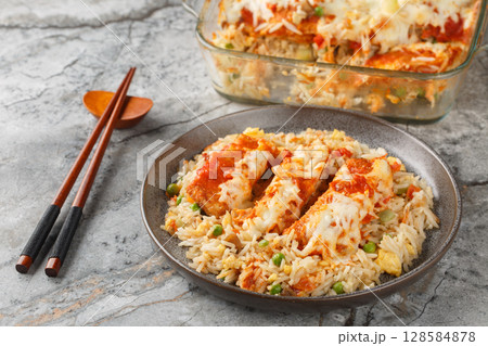 Hong Kong food baked pork chop with fried rice, tomato sauce and melted cheese on top close-up in plate on table. Horizontal Hong Kong food baked pork chop with fried rice, tomato sauce and melted cheese on top close-up in plate on table. Horizontal 128584878