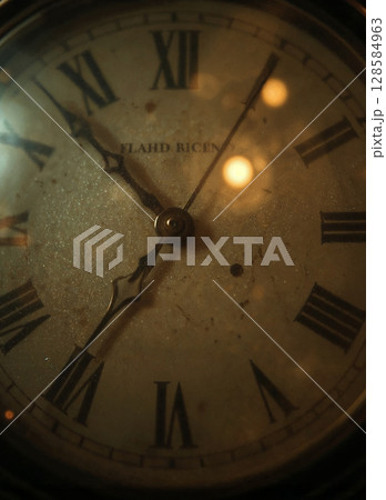 Extreme close-up of a vintage clock face with Roman numerals. The dusty, weathered surface and warm, moody lighting evoke a sense of nostalgia and the passage of time. Antique and retro concept. 128584963