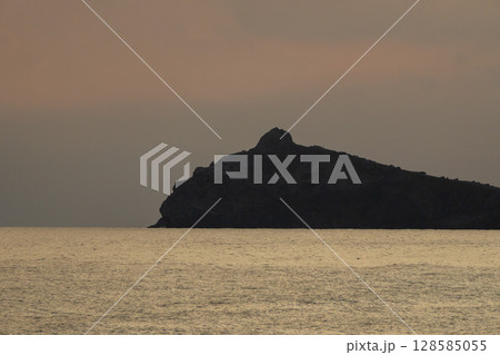 Sunset Seascape Mountain Silhouette Calm: Dramatic evening view with dark mountain against golden sea, creating peaceful scenery. 128585055