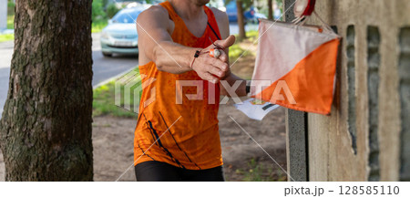 An athlete in street orienteering registers a control point with an electronic chip on their finger. An athlete in street orienteering registers a control point with an electronic chip on their finger. 128585110