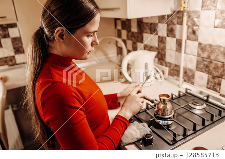 Woman Coffee Preparation Kitchen: Brewing Turkish coffee stovetop home evening. 128585713