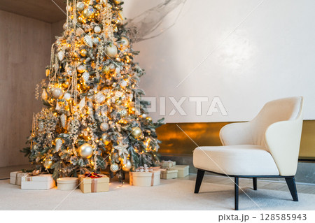 Classical Christmas decorated interior living room. Modern classic style interior design apartment with cozy chair and Christmas tree with white golden ornament decorations. Christmas eve at home 128585943