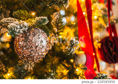 Merry Christmas Xmas happy holidays. Golden ornament decoration ball and defocused garland lights on classic decorated Christmas tree. Christmas tree with red white ornaments. Christmas eve at home 128585950