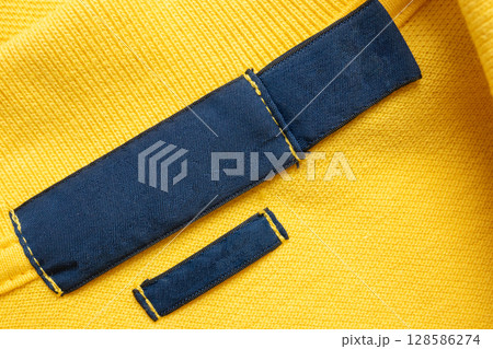 Blank blue laundry care clothes label on yellow shirt fabric texture background 128586274