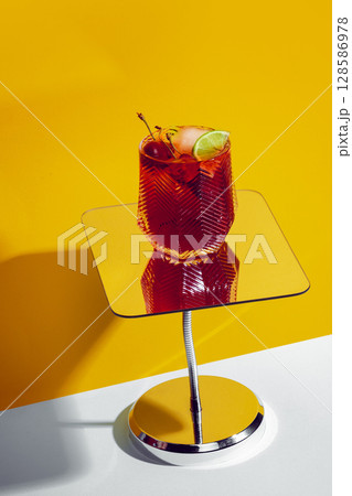 Sleepy Girl Mocktail on mirrored stand with lime and cherry under yellow lighting 128586978