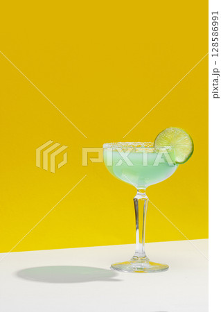 Agave lime margarita cocktail with fresh lime on yellow background Agave lime margarita cocktail with fresh lime on yellow background 128586991