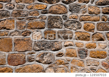 Rustic stone wall with varied textures and earth tones 128587010