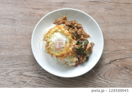 spicy stir fried slice beef meat with basil leaf and chili on rice topping egg in plate spicy stir fried slice beef meat with basil leaf and chili on rice topping egg in plate 128589045