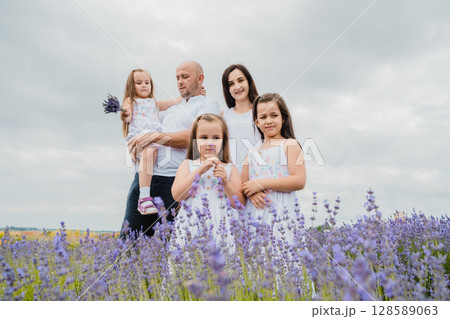 The father, wearing a white T-shirt, holds one of his daughters in his arms in the lavender field 128589063