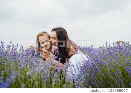 In the lavender field, the mother gently holds her daughter in her arms 128589067