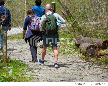 夏の観光名所上高地の散策道でハイキングするシニア男女観光客の姿 128589243