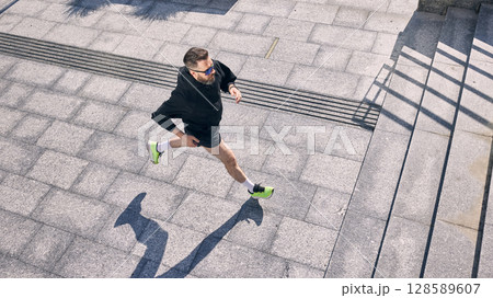 Man jogging on sunny day showcases commitment to midlife fitness and healthy lifestyle 128589607