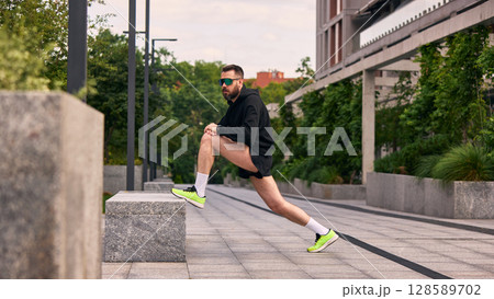 Man extending muscles outside in city park environment endorsing vigorous midlife habits 128589702