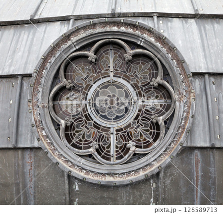 Round stained glass window detail at a historic building in Lourdes 128589713