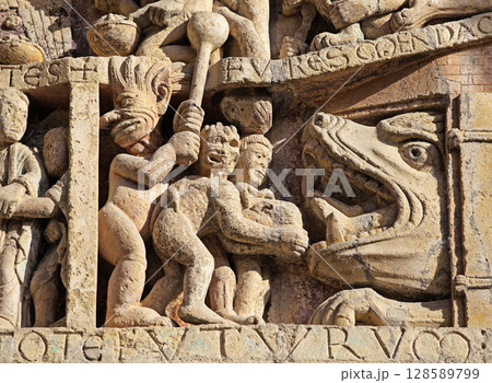 Stone carvings depicting Hell on entrance of Abbey Church of Sainte-Foy in Conques, France 128589799