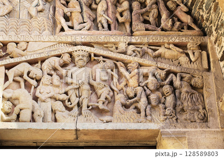 Stone carvings depicting Hell on entrance of Abbey Church of Sainte-Foy in Conques, France 128589803