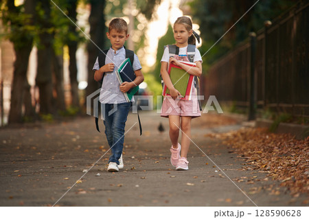 Young school children of boy and girl are together outdoors Young school children of boy and girl are together outdoors 128590628