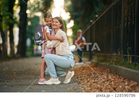 Boy is standing at background. Woman with two kids are going to school, conception of education Boy is standing at background. Woman with two kids are going to school, conception of education 128590786