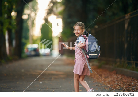 Schoolgirl with backpack is outdoors Schoolgirl with backpack is outdoors 128590802