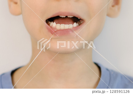 funny little boy flossing his teeth. soft thread of floss silk or similar material used to clean between the teeth 128591126