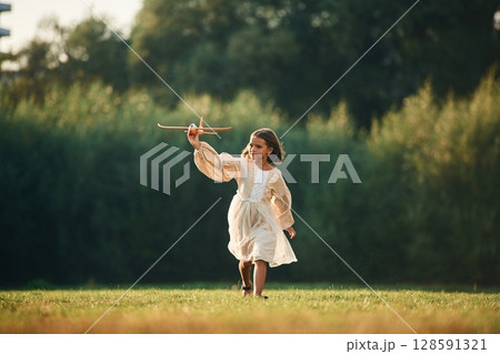 Running with toy plane. Little girl is on the summer field outdoors Running with toy plane. Little girl is on the summer field outdoors 128591321