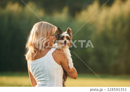 Rear view. Beautiful woman is with her cute dog outdoors on the field Rear view. Beautiful woman is with her cute dog outdoors on the field 128591351
