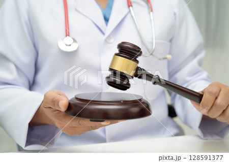 Asian doctor holding court hammer for and crime law justice, forensic medicine. Asian doctor holding court hammer for and crime law justice, forensic medicine. 128591377