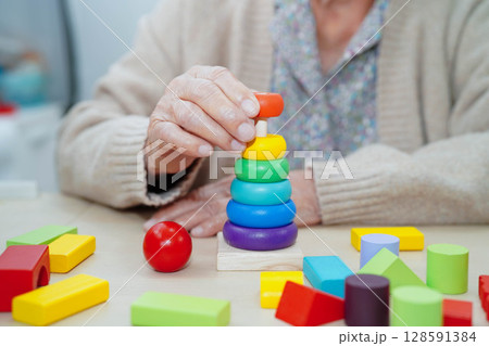 Asian elderly woman playing enhancing skill board game. 128591384