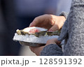 Close-Up of a Fresh Oyster on Ice Held by a Person 128591392
