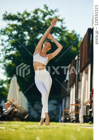 With hands up. Young woman in yoga clothes is outdoors 128591521
