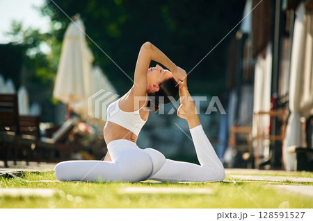 Conception of fitness and flexibility. Young woman in yoga clothes is outdoors Conception of fitness and flexibility. Young woman in yoga clothes is outdoors 128591527