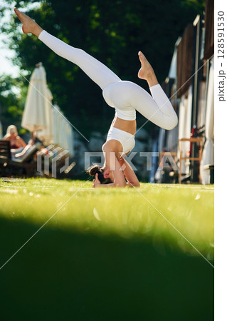 Doing head stand. Young woman in yoga clothes is outdoors Doing head stand. Young woman in yoga clothes is outdoors 128591530