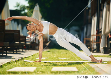 On the right hand and leg. Young woman in yoga clothes is outdoors 128591539