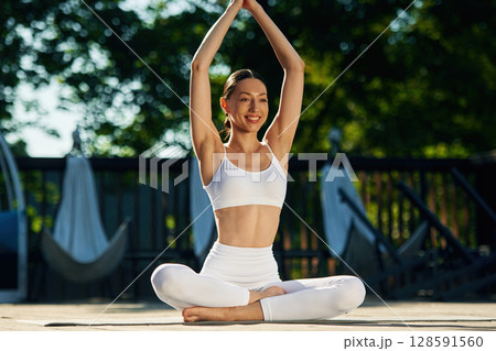 With hands up. Young woman in yoga clothes is outdoors With hands up. Young woman in yoga clothes is outdoors 128591560