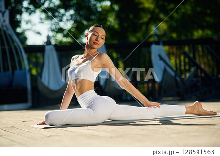 Strength and flexibility. Young woman in yoga clothes is outdoors 128591563