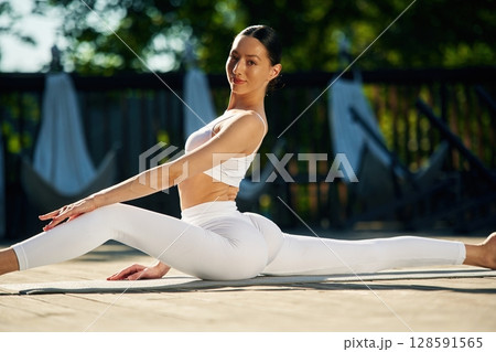 Strength and flexibility. Young woman in yoga clothes is outdoors 128591565